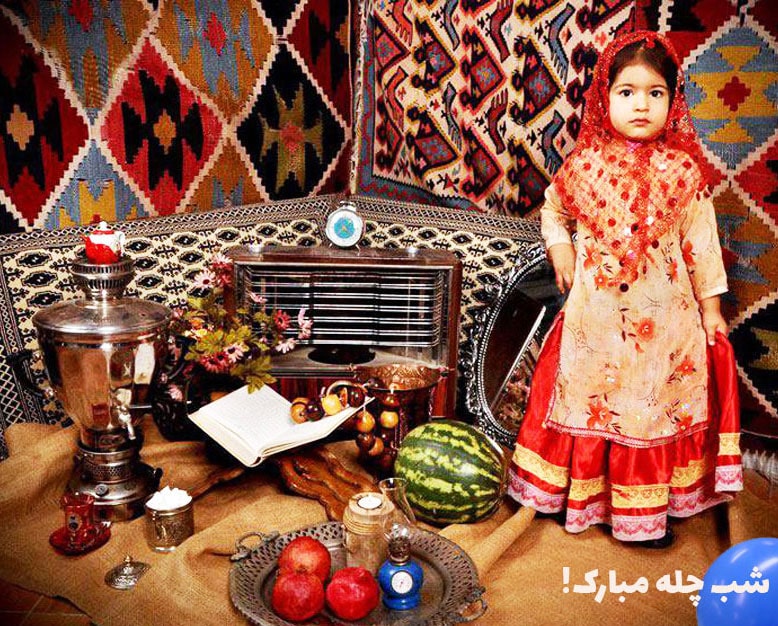 تصویر دختربچه با لباس محلی در کنار سفره یلدا